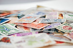Closeup view on a variety of multi-colored postage stamps from different countries and years. Selective focus