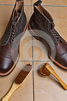 Closeup View of Various Shoes Cleaning Accessories for Dark Brown Grain Brogue Derby Boots Made of Calf Leather Over Tile