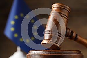 Closeup view of wooden judge`s gavel and European Union flag on blurred background, closeup. Space for text