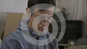 Closeup view of young adult man worker in a glasses using smart phone at factory