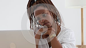 Closeup view of young African American woman looking at computer screen at table in home spbi.