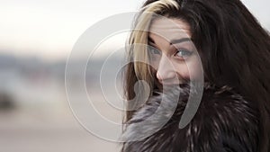 Closeup view of young attractive woman`s face looking in the camera and smiling. She is running forward and turning