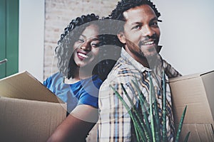 Closeup view of Young black african man and his girlfriend moving boxes into new house together and making a beautiful