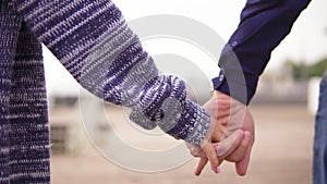 Closeup view of a young couple on the beach holding hands and walking together. Slowmotion shot