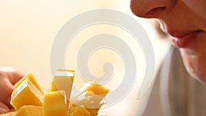 Closeup view of young woman eating juicy ripe mango