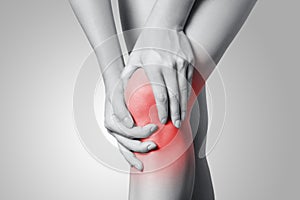 Closeup view of a young woman with knee pain on gray background.