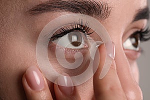 Closeup view of young woman putting contact lens in her eye