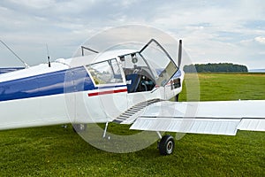 Closeup view of Zlin Z-43 four-seat airplane standing on a grass runway.