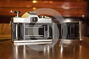 Closeup of a vintage camera with a black leather part on a wooden table on a blurry background