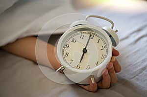 Closeup vintage clock in a boy hand showing 6am 6 oclock in the morning.