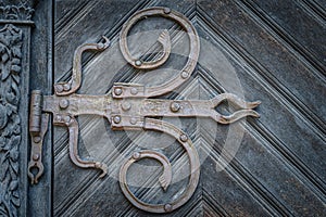 Closeup on vintage iron hinges in baroque style on wooden door