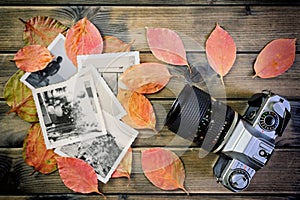 Closeup of vintage photo and camera on antique wooden table and leaves background