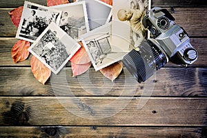 Closeup of vintage photo and camera on antique wooden table and leaves background