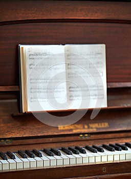 Closeup of a vintage piano and keyboard with a sheet music book. An empty antique or wooden musical instrument for