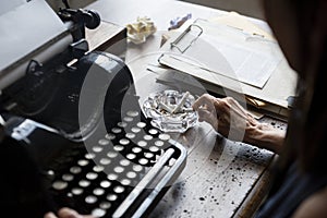 Closeup of vintage retro typewriting with hand and cigarette ashtray