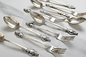 Closeup of vintage spoons and fork with decorative handles on the white table