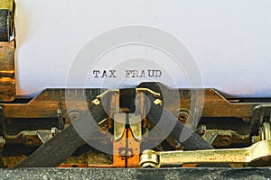 Closeup on vintage typewriter. Front focus on letters making TAX FRAUD text. Business concept image with retro office tool