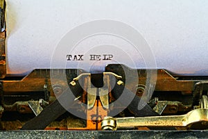 Closeup on vintage typewriter. Front focus on letters making TAX HELP text. Business concept image with retro office tool