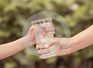 Closeup vintage woman hand giving glass of fresh water to child