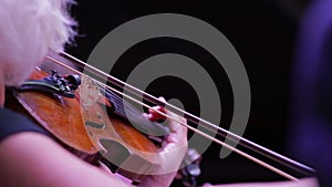 Closeup of a violin and hand with a bow. Symphony Orchestra. Violinists' performing. Classical music