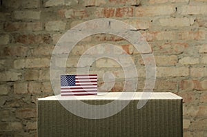 Closeup of voting box and American flag on it against brick wall photo