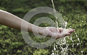 Closeup water flow to hand of women for nature concept on the garden background