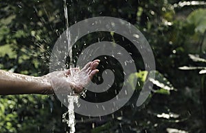 closeup water flow to hand of women for nature concept on the garden background