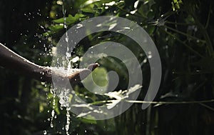 closeup water flow to hand of women for nature concept on the garden background