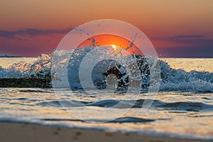 Closeup of a water wave swashing on the sea at sunset, purple sky background