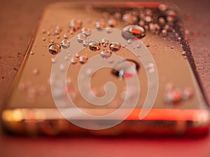 Closeup of waterdrops on a phone screen in neon light