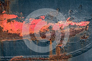 Closeup of a weathered ship hull with rust and red lead