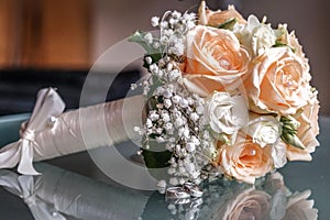 Closeup of a wedding bouquet next to wedding rings on glass