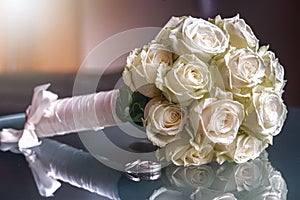 Closeup of a wedding bouquet next to wedding rings on glass