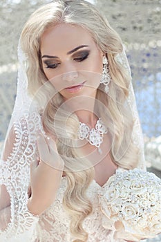 Closeup wedding portrait of gorgeous bride. Beautiful blond woman with long wavy hair style and makeup wearing in fashion bridal