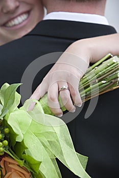 Closeup of wedding ring with bride and groom in background