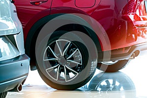 Closeup wheel of red car parked in showroom. Wheel and tire of new car. Car dealership business concept. Auto leasing and car