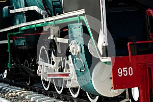 Closeup wheel of train. Green red and white train. Antique vintage train locomotive. Old steam engine locomotive. Black locomotive