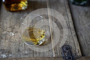 Closeup of whisky glass and bottle on a shabby wooden barrel