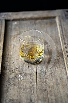 Closeup of a whisky glass on a shabby rustic wooden furniture