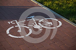 Closeup of white bicycle sign on the sunlit bike lane in the park