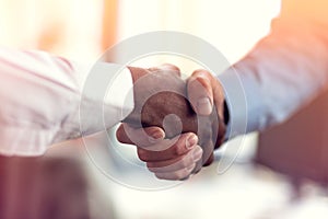 Closeup of White and Black shaking hands over a deal