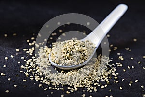 Hulled hemp seeds on a dark gray surface