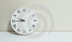 Closeup white clock for decorate show a quarter to ten or 9:45 a.m. on white wood desk and cream wallpaper textured background wit