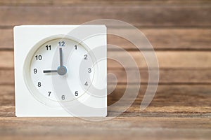 Closeup white clock showed nine o `clock on blurred brown wood board background photo