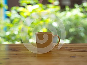 Closeup White Cofee Cup on the wooden table with a green leaf bokeh.