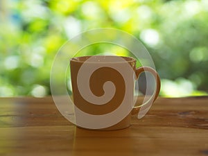 Closeup White Cofee Cup on the wooden table with a green leaf bokeh.