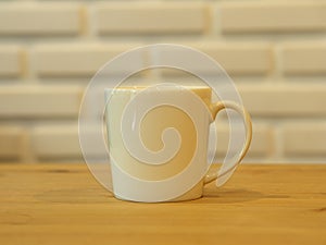 Closeup White Cofee Cup on the wooden table with White Brick wall background.