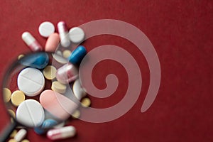 Closeup of white and color pils and capsules on red background. medical background