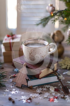 Closeup white cup of coffee on the festive table and gift boxes on wooden background. Christmas or New Year