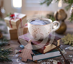 Closeup white cup of coffee on the festive table and gift boxes on wooden background. Christmas or New Year